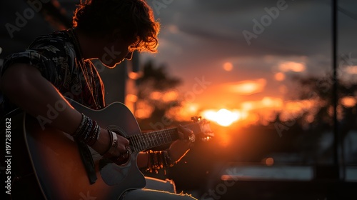A young man plays his acoustic guitar with passion as the sun sets, creating a beautiful and dramatic silhouette in the evening light.