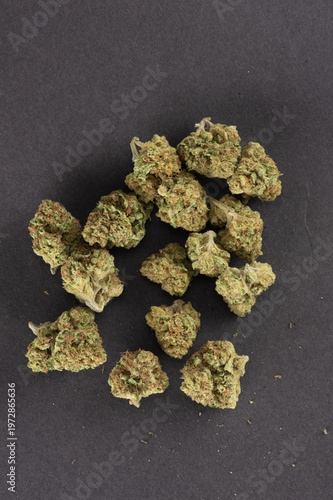 Several dried cannabis buds arranged on a dark surface.