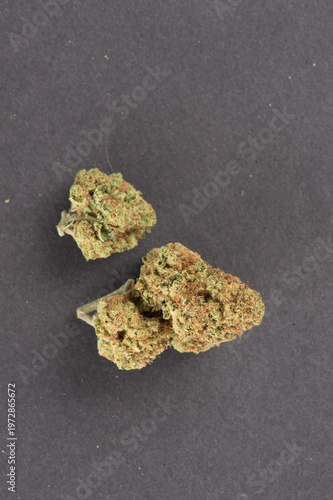 Three dense cannabis buds with visible orange hairs and frosty trichomes on a dark gray background.
