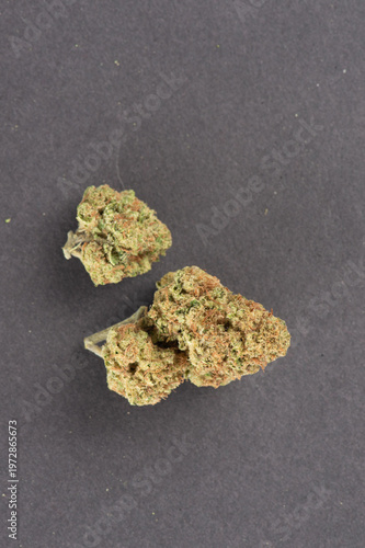 Three cannabis buds with green and orange hues are displayed on a dark background.
