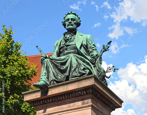 A bronze statue of a seated man with a book