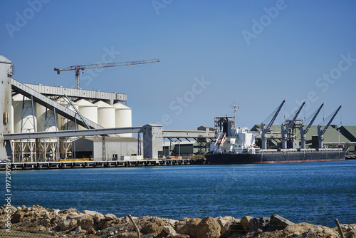Cargo ship docked at Geralton Port Western Australia view of loading cranes on a clear day