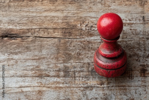 Vintage Red Wooden Chess Pawn on Weathered Wood Surface.