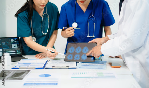 Doctors and nurses reviewing brain scan on tablet for diagnosis, teamwork and data analysis in modern hospital, professional healthcare service