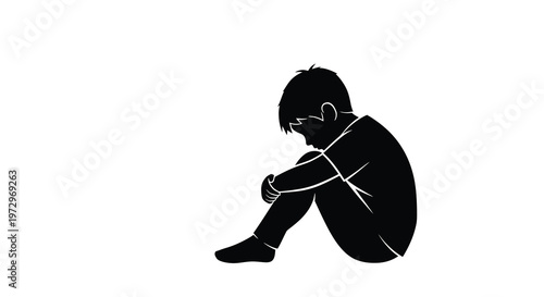 Silhouette of a child sitting with knees drawn up appearing distressed