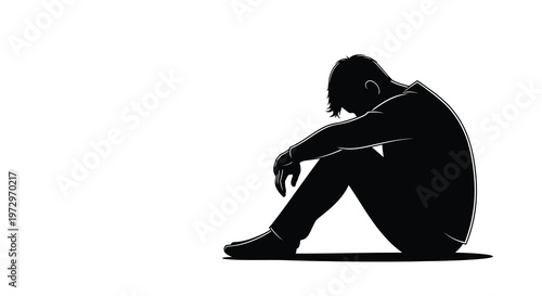 Silhouette of a man sitting and appearing dejected or lost in thought