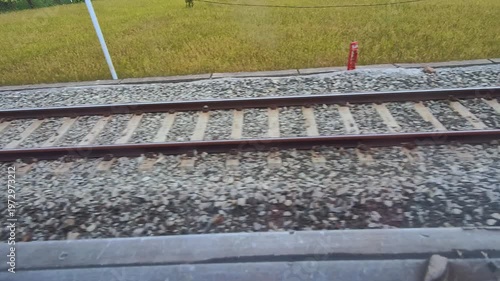 Video of a view of a rusty train track with gravel and rail sleepers from the POV of a passenger sitting on a moving train. Footage of the track for the train's wheels to run steadily, safely, and eff