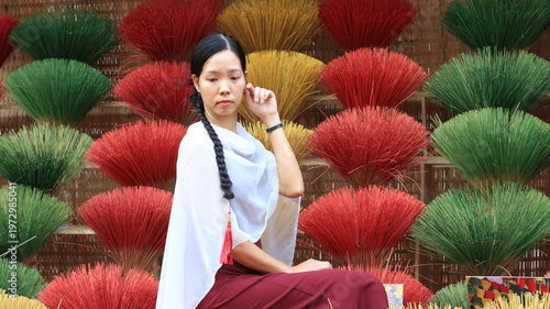 Vietnamese model in a red and white dress in front of a traditional display. 