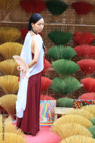 Vietnamese model in a red and white dress in front of a traditional display. 