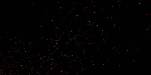 Blur, bokeh, fire, red light, tiny specks created by the heat energy of burning fuel on a black background.