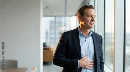 Mature business executive pausing for controlled breathing by office window during stressful workday with copy space for workplace wellness and recovery communication