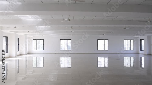 Empty Industrial Hall with Polished White Floor Windows and Ceiling Fans in Large Commercial Space.
