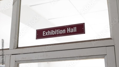Low Angle View of Exhibition Hall Door Signage Mounted on Glass Partition in Corporate Setting.
