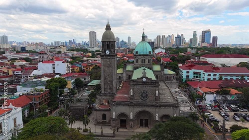 Aerial drone view of Manila Cathedral in Intramuros with modern skyline in the background. Historic architecture meets urban cityscape in Manila, Philippines.