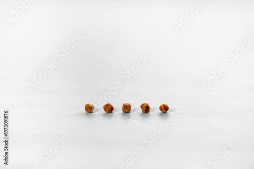 five brown gallbladder lumps or pile gallstones ball lined up group and many kidney stones from cholesterol or bad food on white table for medical science background isolated with copy space