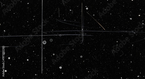 Abstract black background with white dust particles, scratches, and grunge texture, resembling an old film overlay or distressed surface.