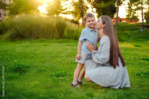 mom and child playing on a green lawn in the park in the summer, having fun together, mother and small child walking in the summer, playing on the grass