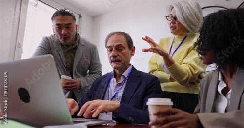 Multiethnic team of professionals discussing a new project on a laptop in a modern boardroom. Business people are brainstorming and collaborating, looking at the computer screen together