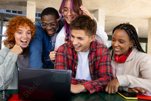 Diverse group of friends collaborating on laptop