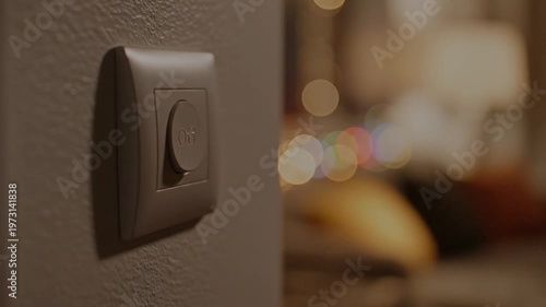 Human finger pressing illuminated Off button on wall switch