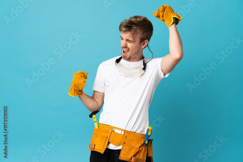 Young electrician man over isolated wall celebrating a victory