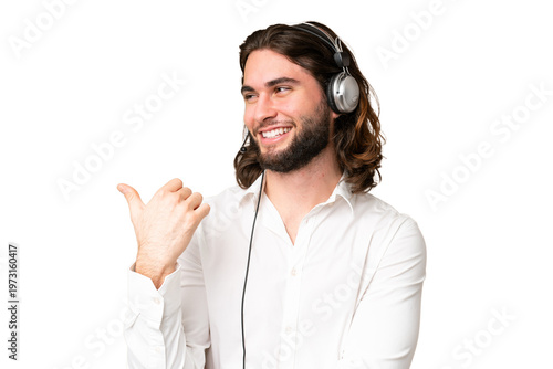 Telemarketer man working with a headset over isolated chroma key background pointing to the side to present a product