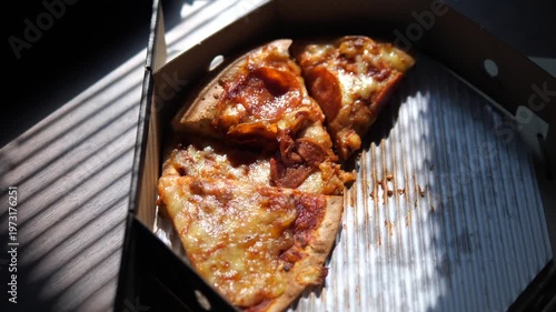 Leftover pepperoni pizza slices in delivery box under window blind shadows for lonely dining or late night snack concept