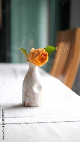 Vertical close-up of withered orange rose in a ceramic vase representing sadness ending and fading memories concept