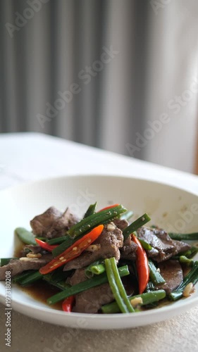 Vertical close-up of healthy stir-fried pork liver with green onions and chili served on a white plate for Asian dining concept