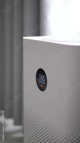 Modern white air purifier with digital display showing high PM 2.5 dust levels in a room for healthy home and pollution concept