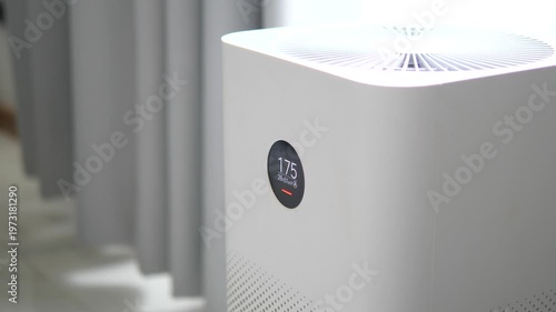 Modern white air purifier with digital display showing high PM 2.5 dust levels in a room for healthy home and pollution concept