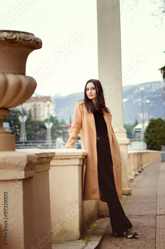 A peaceful young woman strolls along a city street, lifestyle style. Concept of self-connection, quiet strength, and modern feminine presence in an urban setting. Vertical photograph.