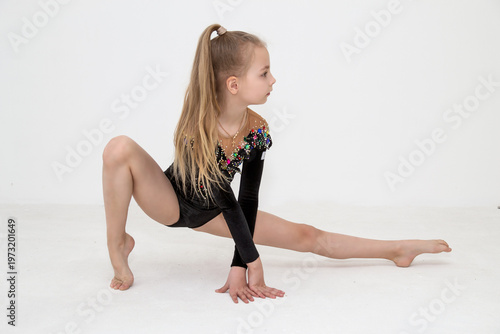 A young rhythmic gymnast in a beautiful velvet black leotard is training.