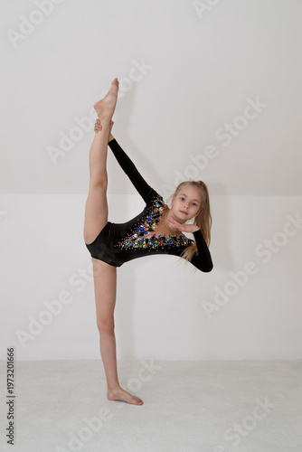A young rhythmic gymnast in a beautiful velvet black leotard is training.