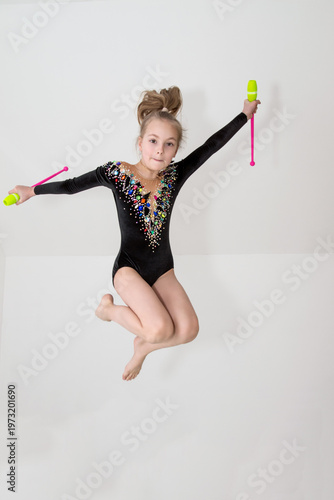A young rhythmic gymnast in a beautiful velvet black leotard is training.