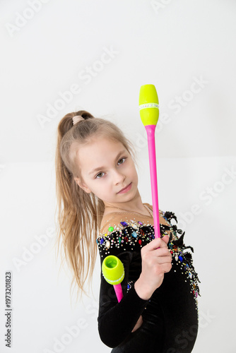 A young rhythmic gymnast in a beautiful velvet black leotard is training.