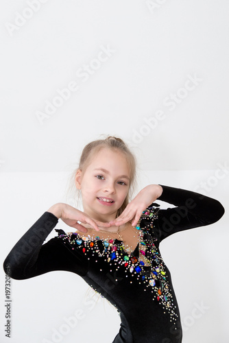 A young rhythmic gymnast in a beautiful velvet black leotard is training.