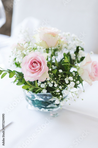 Tableau sur toile Elegant floral centerpiece with soft pink roses and white baby's breath in a crystal bowl on a white tablecloth