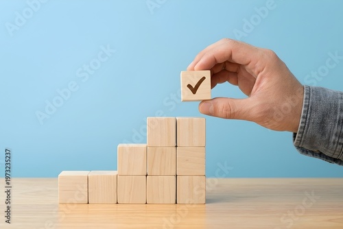 Eye-Level Close-Up Hand Holding Light Wooden Block with Dark Check Mark Denim Pattern Light Blue Background Minimalist Professional Style lighting