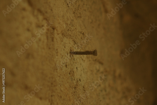 Single rusty nail on a weathered plaster wall