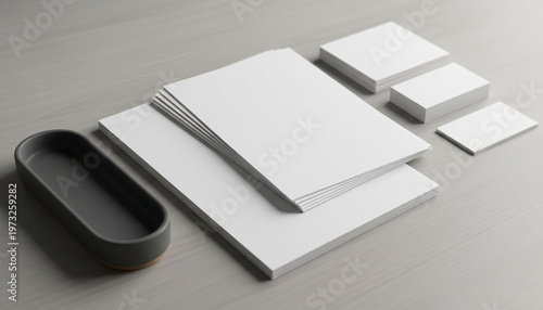 White paper stacked on a table with a gray container and smaller cards arranged around it for organized workspace