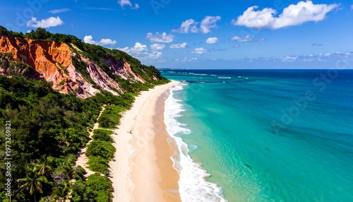 A stunning aerial view captures a pristine sandy beach alongside vibrant turquoise ocean waters, nestled between colorful cliffs under a bright, cloud-dotted sky