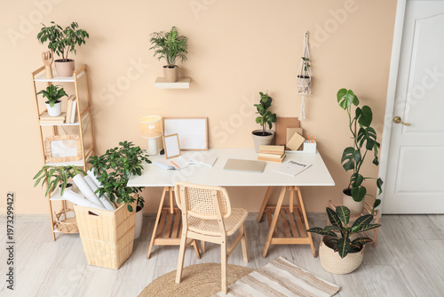 Interior of stylish office with comfortable workspace, books, modern laptop a...