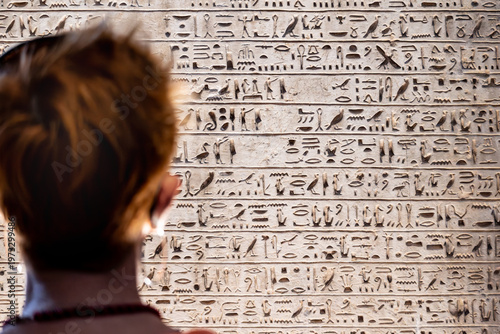 Big stone slab with many even lines of carved ancient Egyptian hieroglyphs and woman head