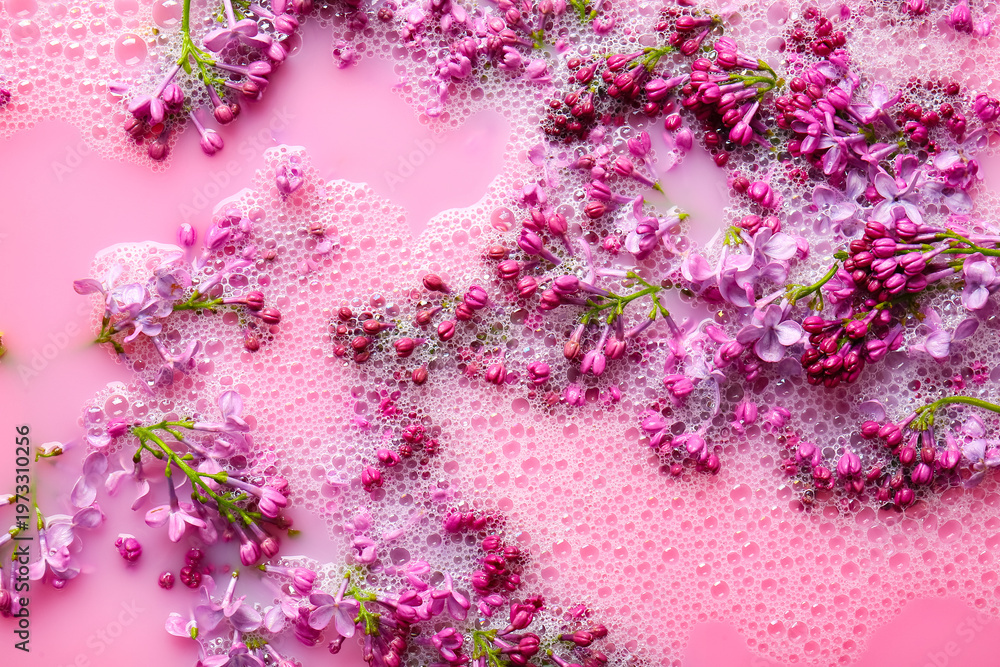 Obraz premium Lilac flowers in pink liquid with soap bubbles, closeup
