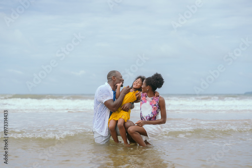 African American family having fun running on the beach on their summer vacation.