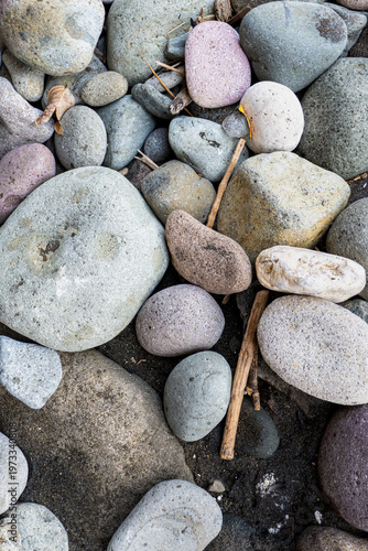 Canvas Print Vertical top view of smooth river stones and pebbles on dark volcanic sand with