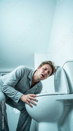 Person in pajamas leaning over a toilet, experiencing vomiting, in a brightly lit bathroom with white tiles and clean, modern fixtures