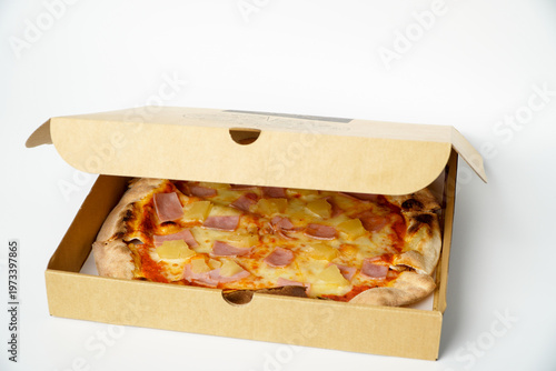 Hawaiian pizza in a box against a white background.