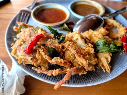 Deep-fried soft shell crab served with dipping sauces and chili, crispy seafood dish with rich texture and vibrant colors